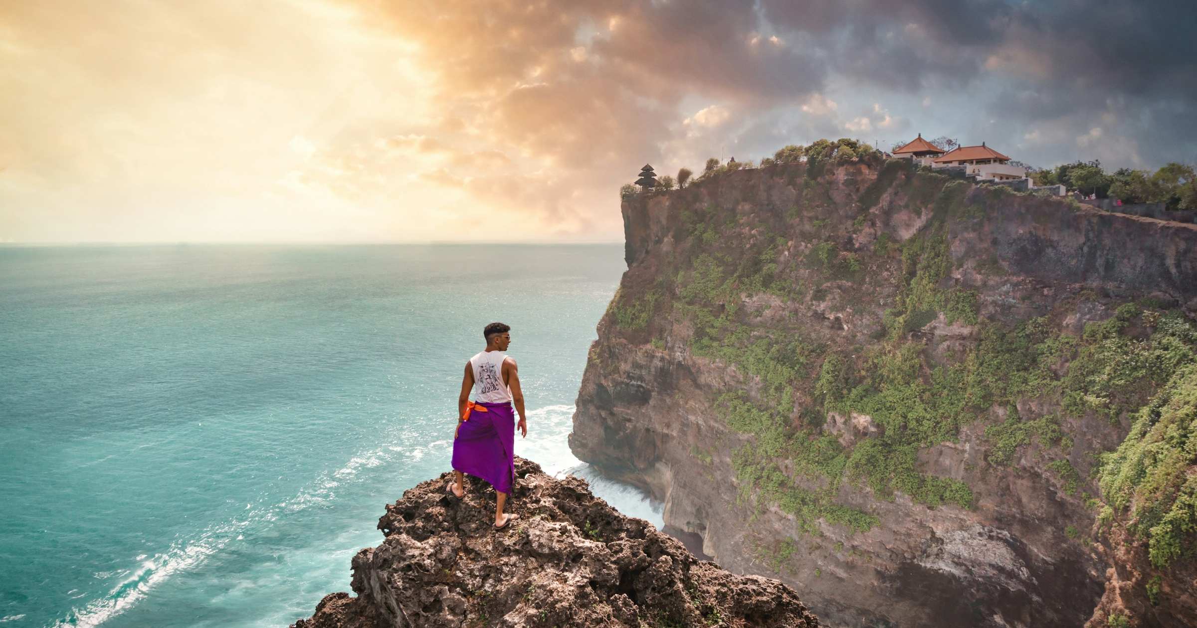 Backpacker looking out over the sea from a clifftop in Bali, Indonesia