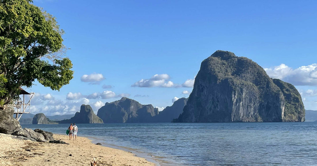 Travellers on a white-sand beach with dramatic karst islands in El Nido, Philippines