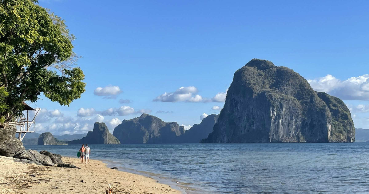 Travellers on a white-sand beach with dramatic karst islands in El Nido, Philippines