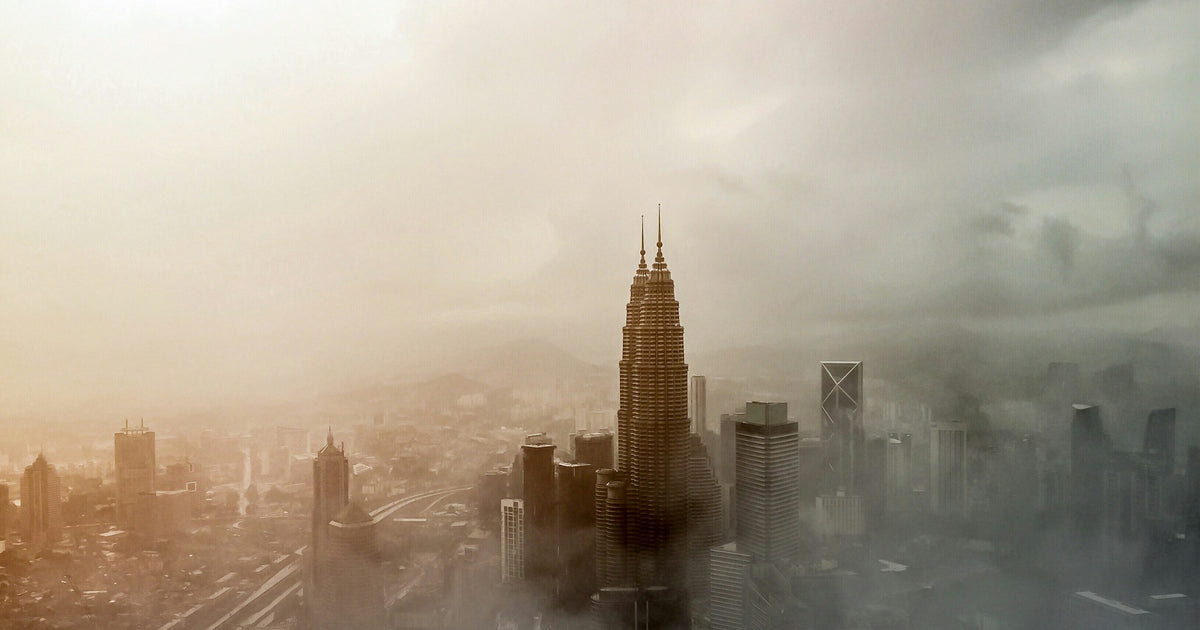 Aerial view of the Petronas Twin Towers rising through cloud over the Kuala Lumpur skyline