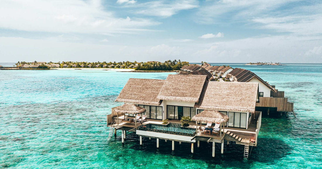 Overwater villas on a turquoise Maldives lagoon, aerial view of a resort island