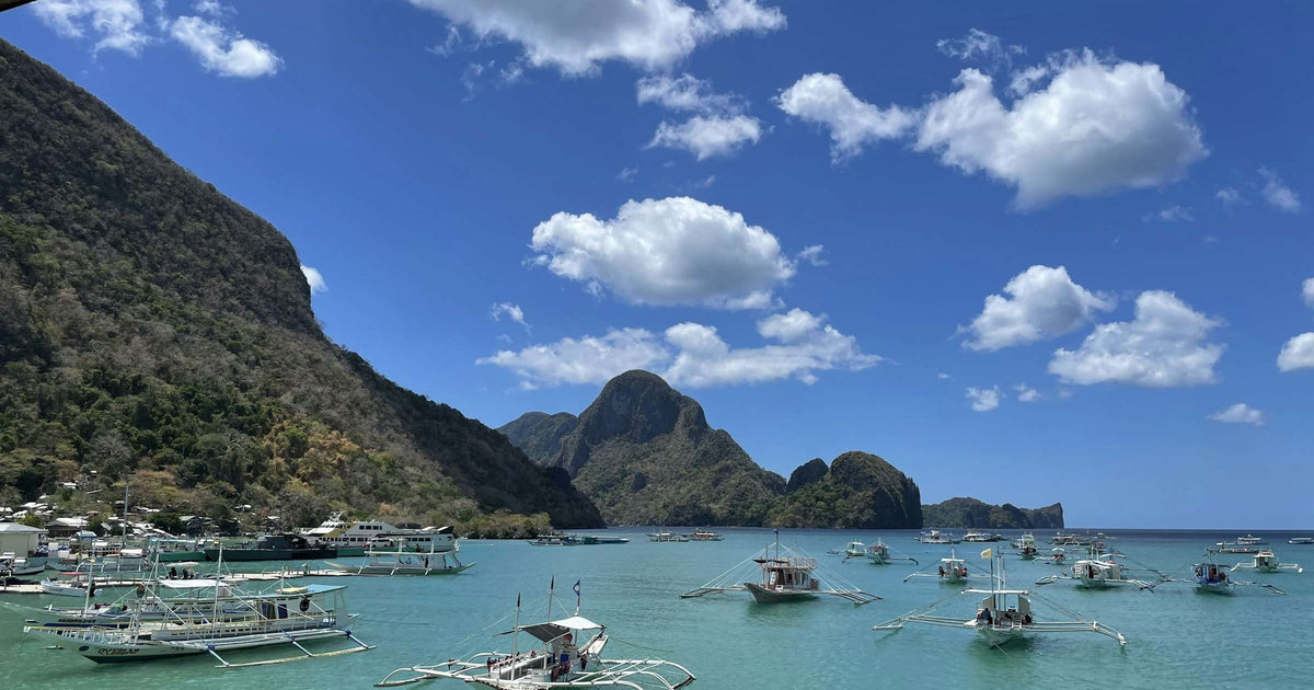 Traditional bangka boats anchored in El Nido harbor with karst limestone mountains in the Philippines