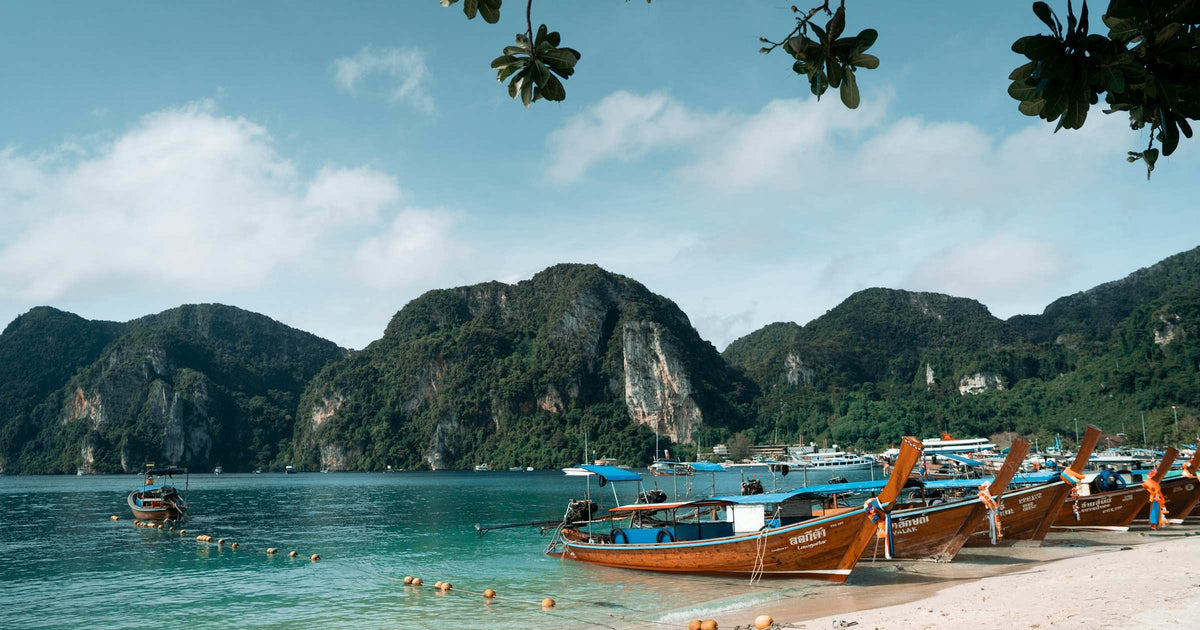 Longtail boats moored on a turquoise beach at Phi Phi Islands on Thailand's Andaman Coast