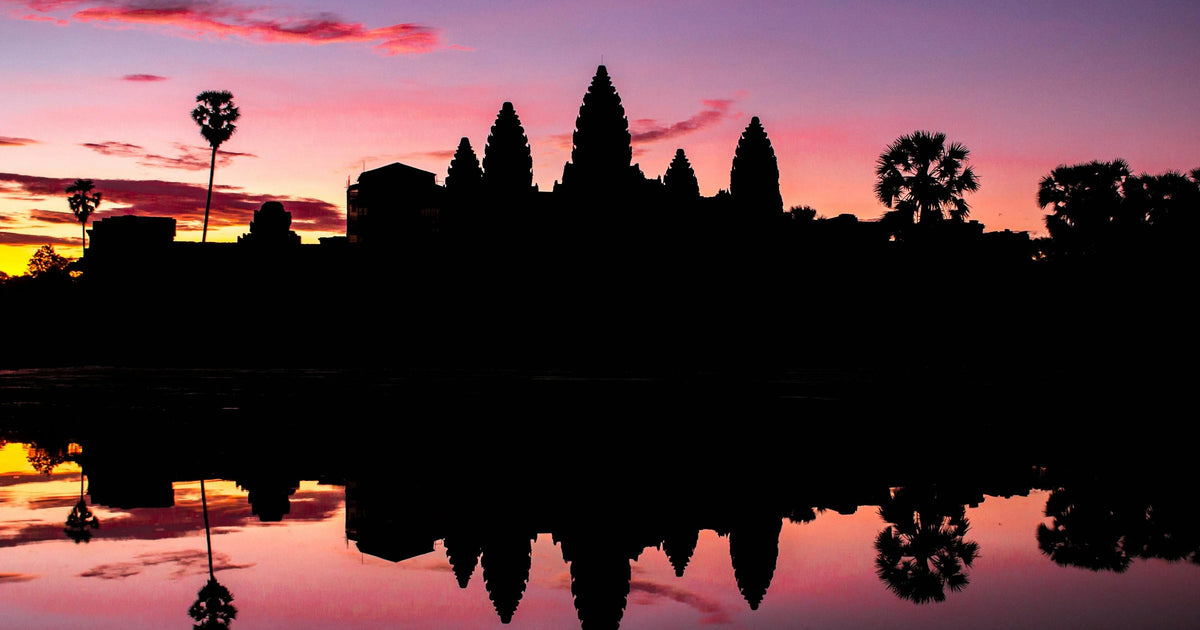 Angkor Wat temple silhouetted at sunrise with pink sky reflected in the lake, Siem Reap, Cambodia