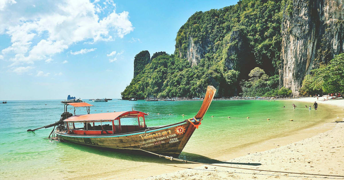 Longtail boat on a turquoise beach in Thailand with limestone karsts in the background